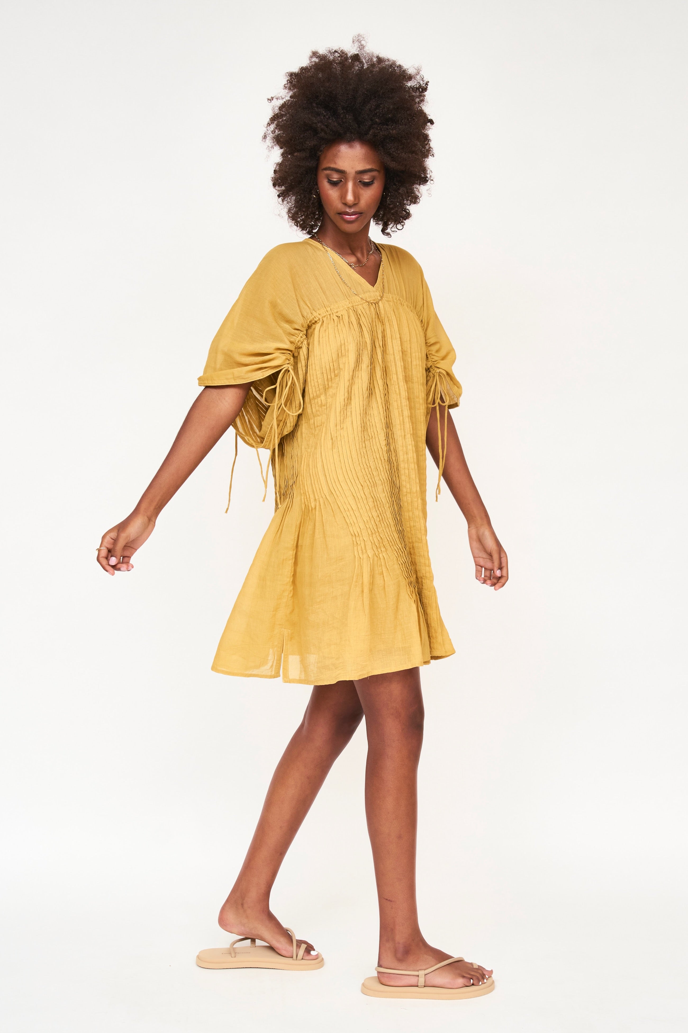 Girl wearing MIRTH women's v neck pleated pull string malta lined coverup short dress in gilded yellow cotton