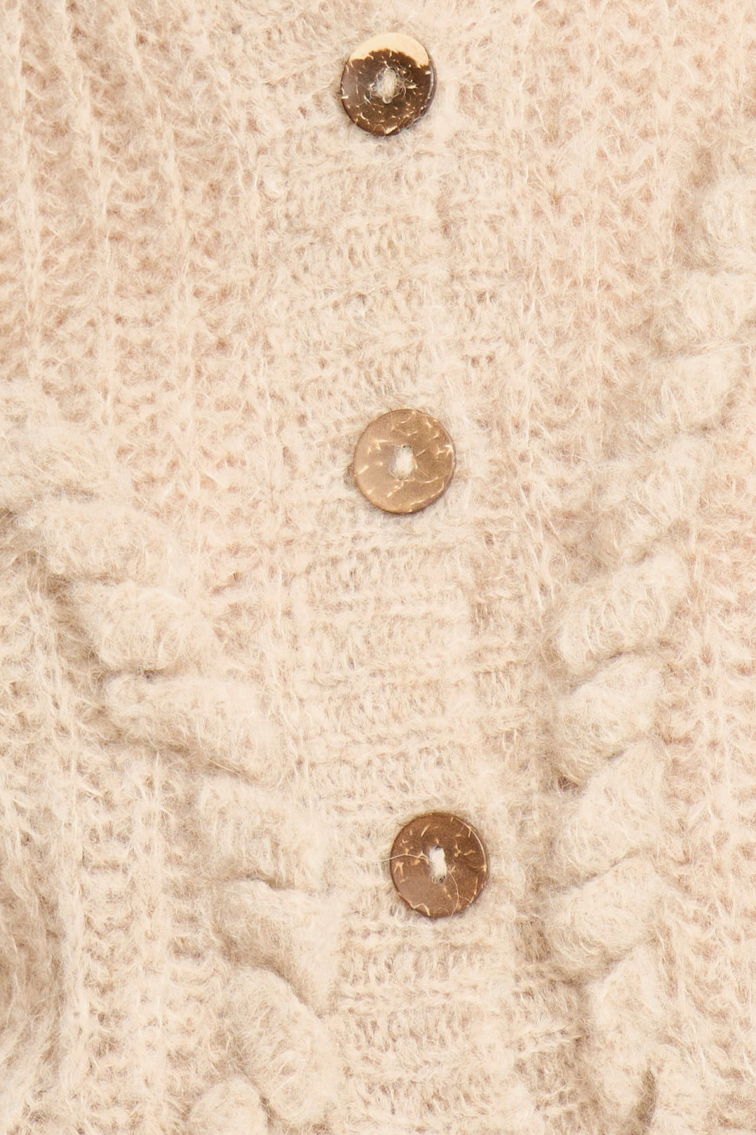 Close-up of a beige knitted fabric with three buttons on a textured background