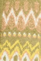 Close-up of a knitted fabric with a pattern featuring wavy lines and small floral elements on a green background.