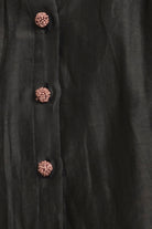 Close-up of a black coat with decorative buttons on a dark background