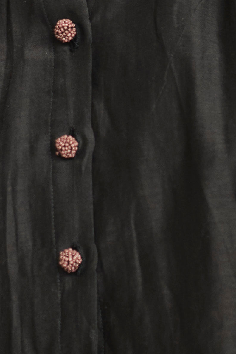 Close-up of a black coat with decorative buttons on a dark background