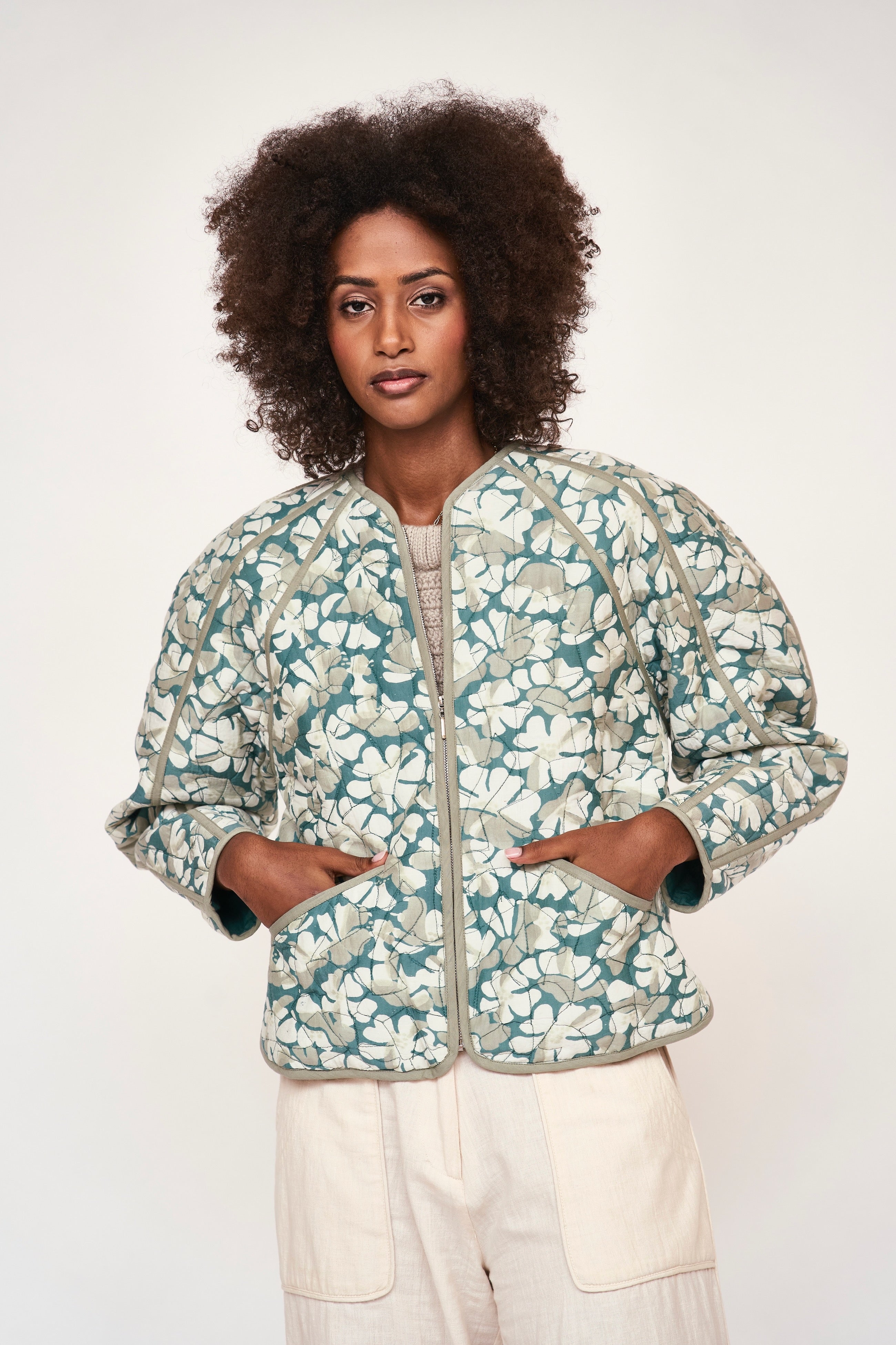 Girl wearing MIRTH women's front zip quilted turin jacket in plumeria blue floral print cotton silk