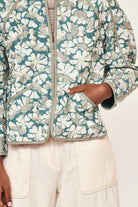 Girl wearing MIRTH women's front zip quilted turin jacket in plumeria blue floral print cotton silk