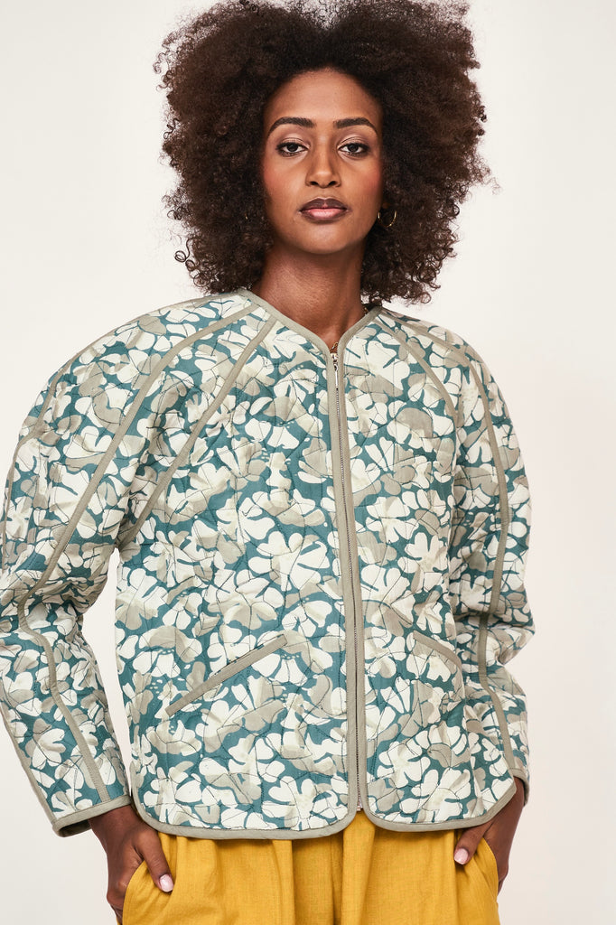 Girl wearing MIRTH women's front zip quilted turin jacket in plumeria blue floral print cotton silk