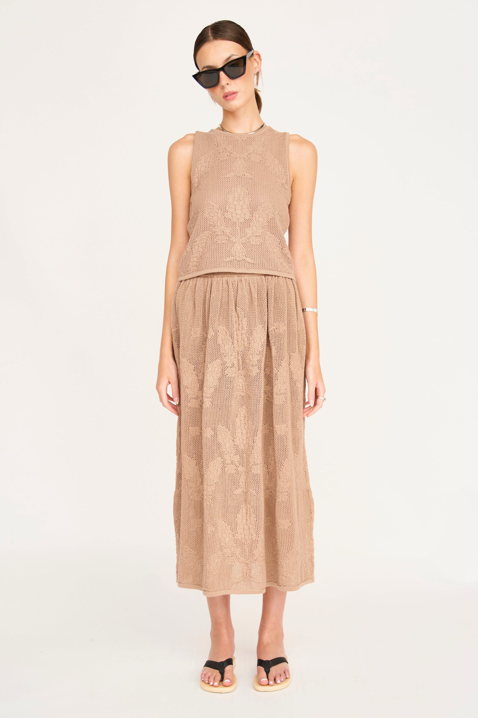 Woman wearing a beige sleeveless top and skirt set on a white background