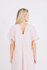 Girl wearing MIRTH women's v-neck tie back bordeaux caftan dress in handloomed light pink rosa cotton jacquard 