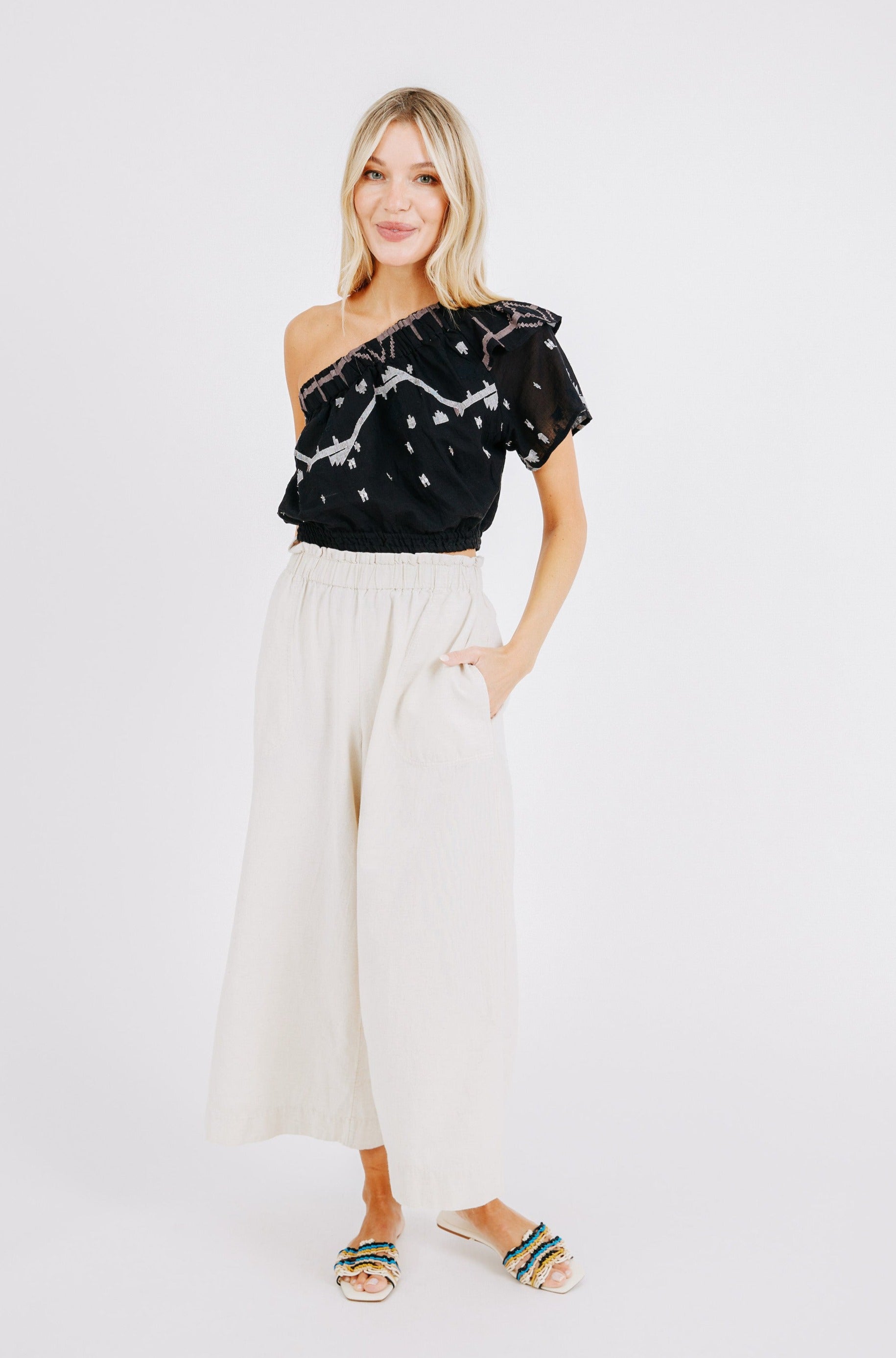 Girl wearing MIRTH women's cropped one shoulder paros top set in handloomed black carnival jamdani