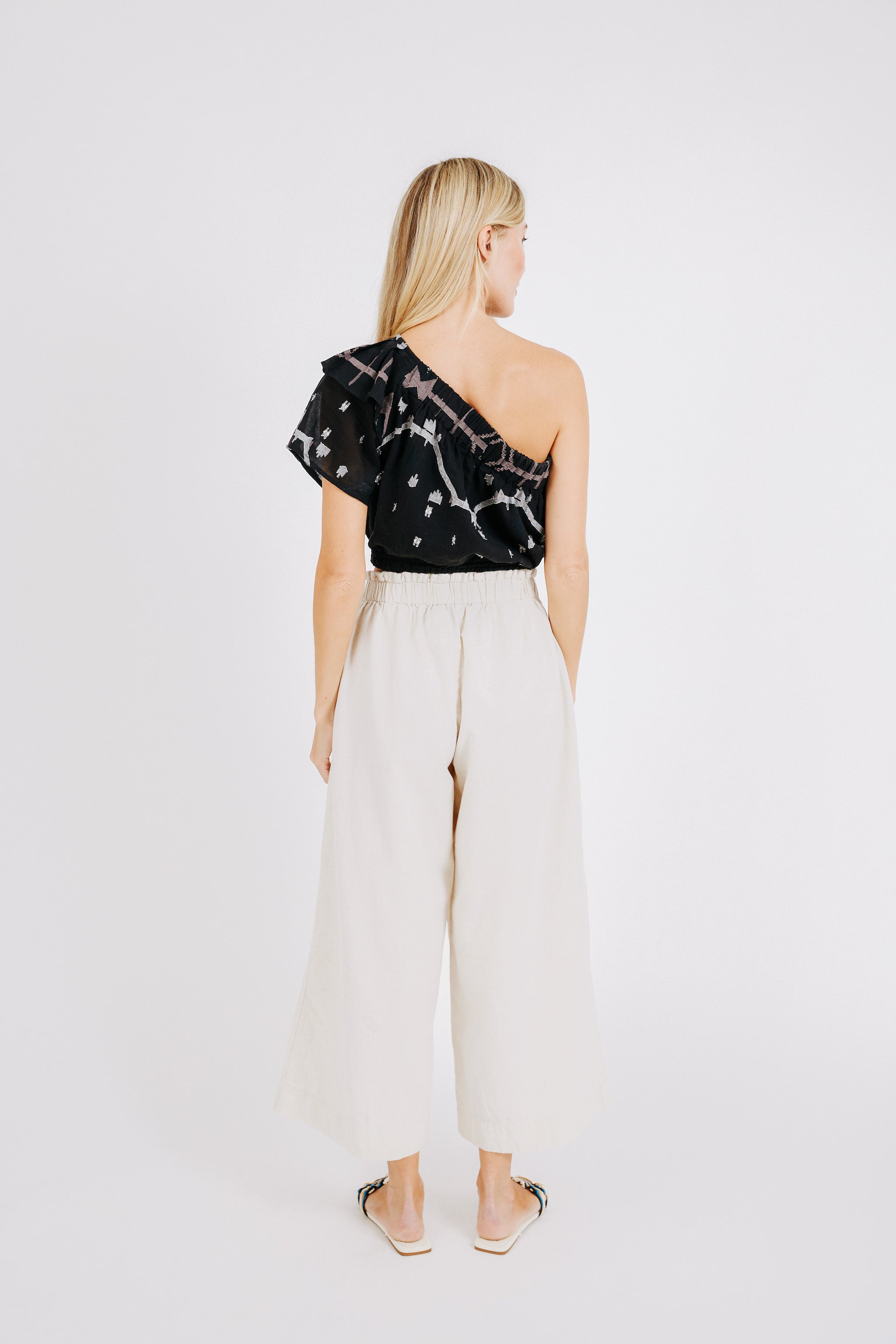 Girl wearing MIRTH women's cropped one shoulder paros top set in handloomed black carnival jamdani