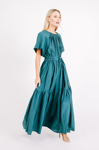 Girl wearing MIRTH women's long tiered gathered short sleeve vienna maxi dress in spruce green cotton silk with tie belt