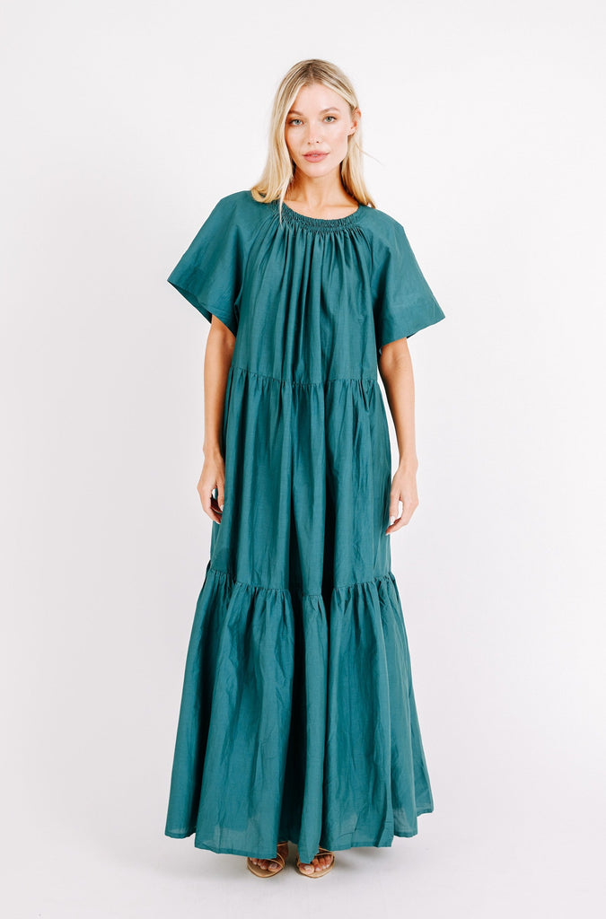 Girl wearing MIRTH women's long tiered gathered short sleeve vienna maxi dress in spruce green cotton silk with tie belt