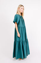 Girl wearing MIRTH women's long tiered gathered short sleeve vienna maxi dress in spruce green cotton silk with tie belt