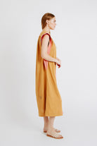 Girl wearing MIRTH women's long pueblo caftan dress in handloomed sedona orange jamdani cotton