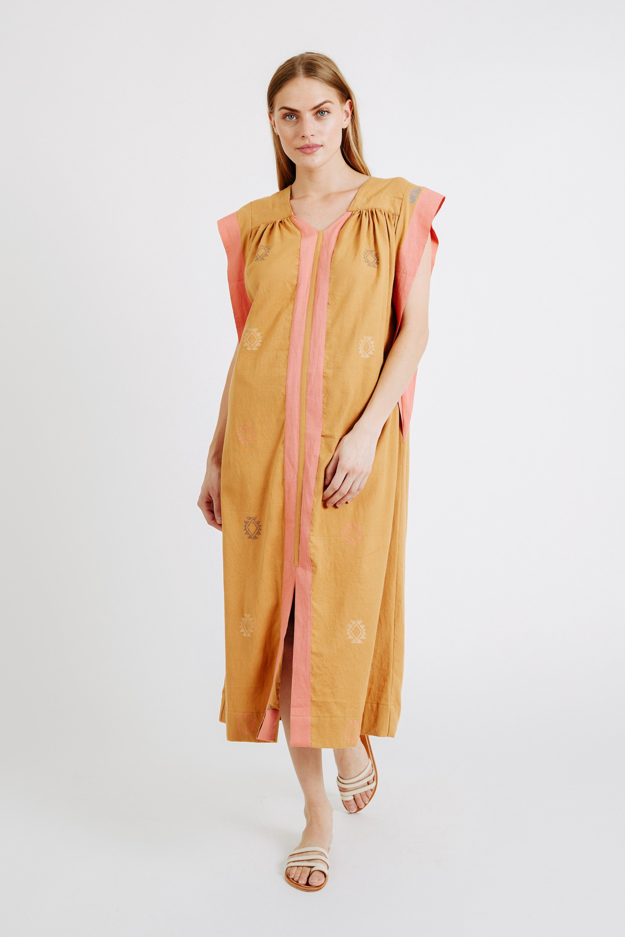 Girl wearing MIRTH women's long pueblo caftan dress in handloomed sedona orange jamdani cotton